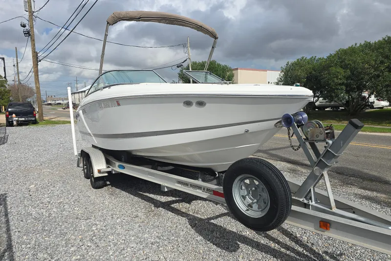 Slide: The Image of 2007 Cobalt 212 boat on trailer, parked on gravel, under cloudy sky. - 1