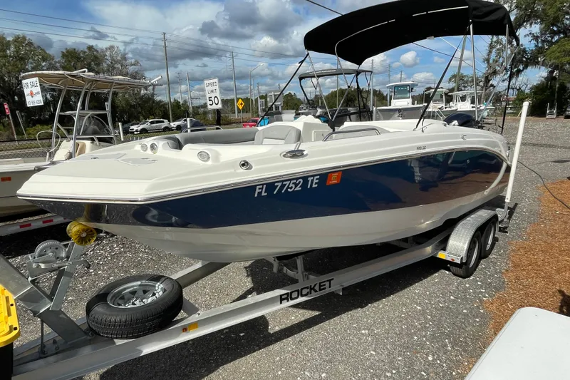Slide: The Image of 2022 NauticStar 223 DC boat on trailer, displayed outdoors under a cloudy sky. - 2