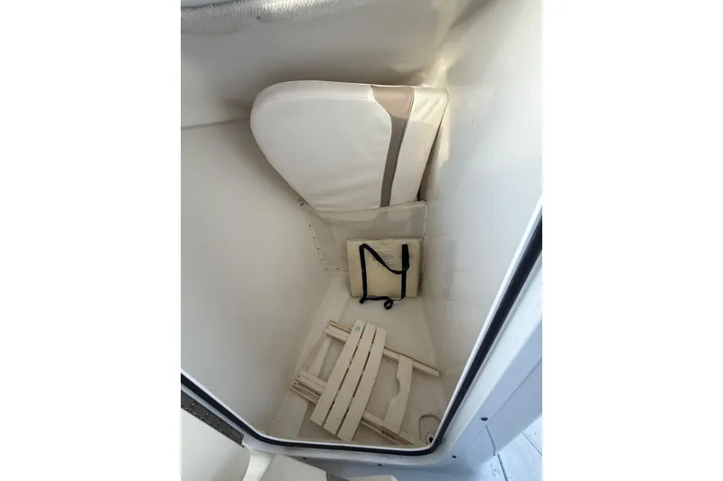 Slide: The Image of Storage compartment in a 2011 Sea Hunt Escape 220 LE boat, featuring cushions and accessories. - 12