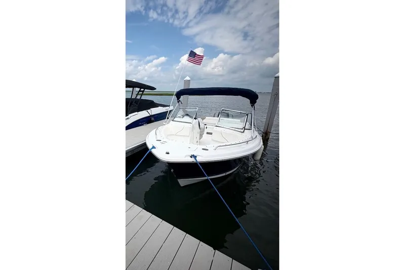 Slide: The Image of 2011 Sea Hunt Escape 220 LE boat docked with American flag, under blue sky. - 2