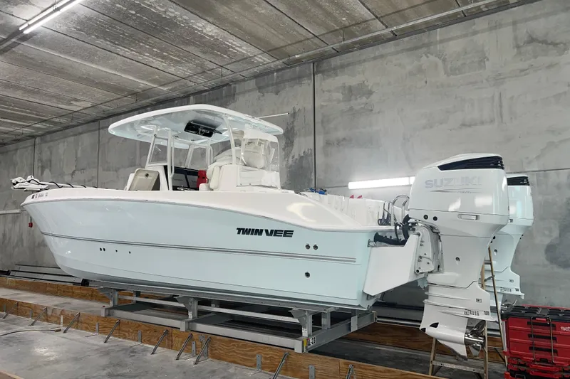 Slide: The Image of 2022 Twin Vee 280 GFX CC boat with Suzuki engines in a storage facility. - 2