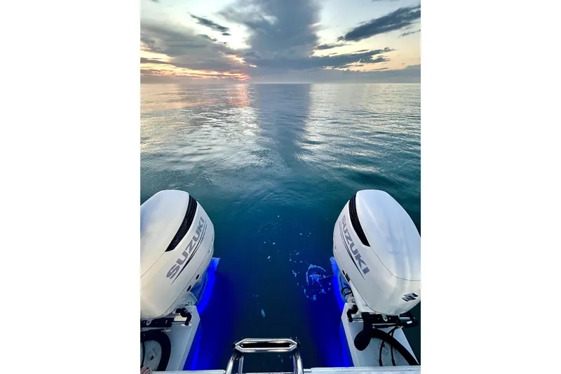 Slide: The Image of 2022 Twin Vee 280 GFX CC boat with Suzuki engines at sunset on calm ocean. - 3