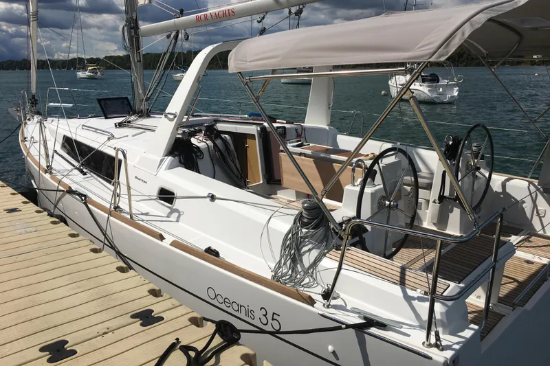 The Image of 2015 Beneteau Oceanis 35 sailboat docked, featuring dual steering wheels and sleek design. - 0