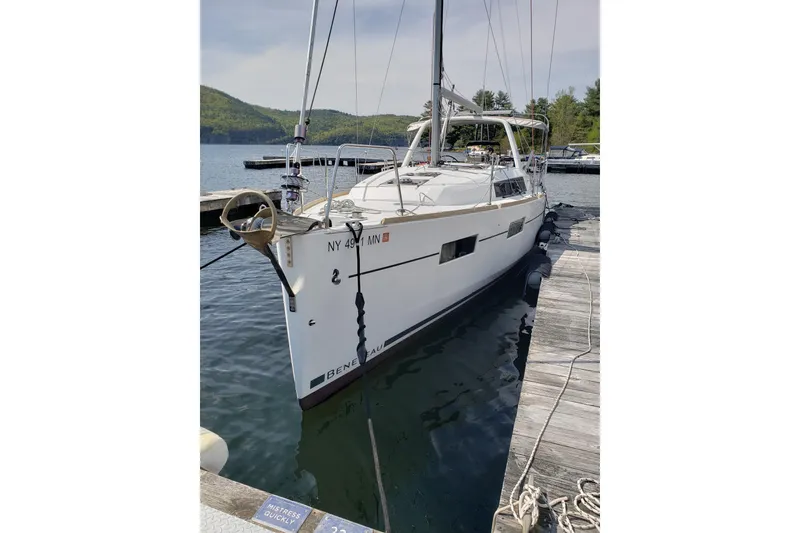 Slide: The Image of 2015 Beneteau Oceanis 35 sailboat docked at a serene lakeside marina. - 3