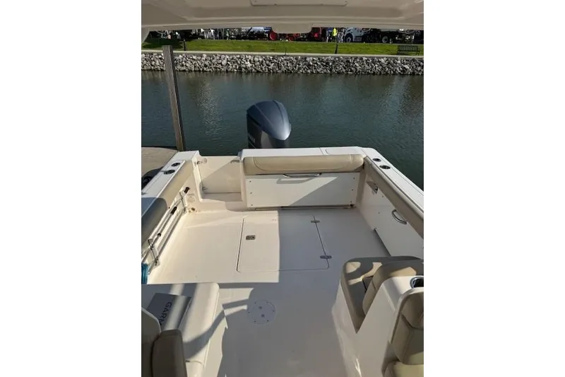 Slide: The Image of 2015 Pursuit DC 265 Dual Console boat interior with seating, docked by water. - 5