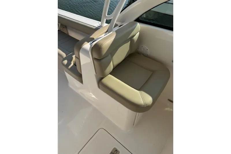 Slide: The Image of 2015 Pursuit DC 265 Dual Console boat seat, beige upholstery, near water. - 7