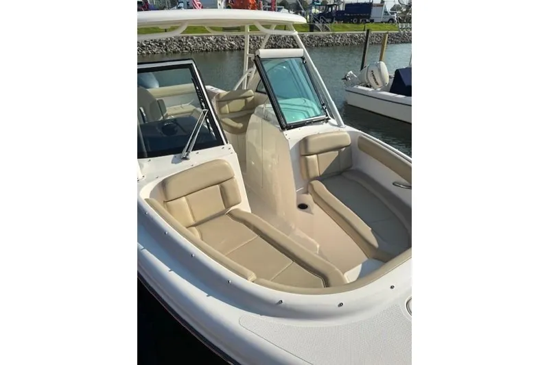 Slide: The Image of 2015 Pursuit DC 265 Dual Console boat with beige seating, docked by the water. - 8