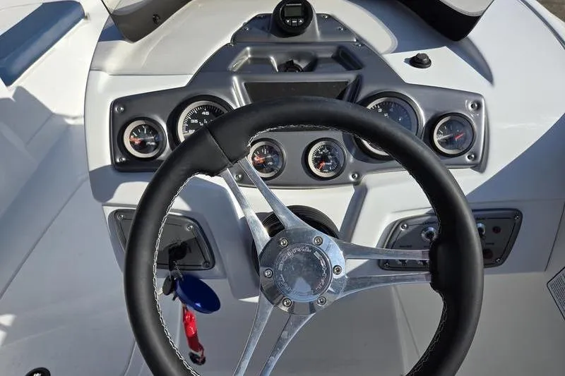 Slide: The Image of Steering wheel and dashboard of 2024 Tahoe 2150 boat, featuring gauges and controls. - 10