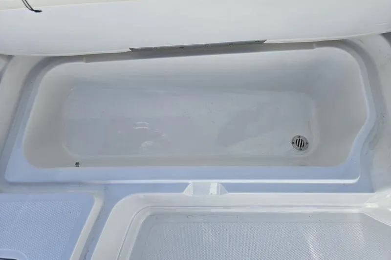 Slide: The Image of 2024 Tahoe 2150 boat storage compartment with drain, featuring a sleek white interior design. - 16