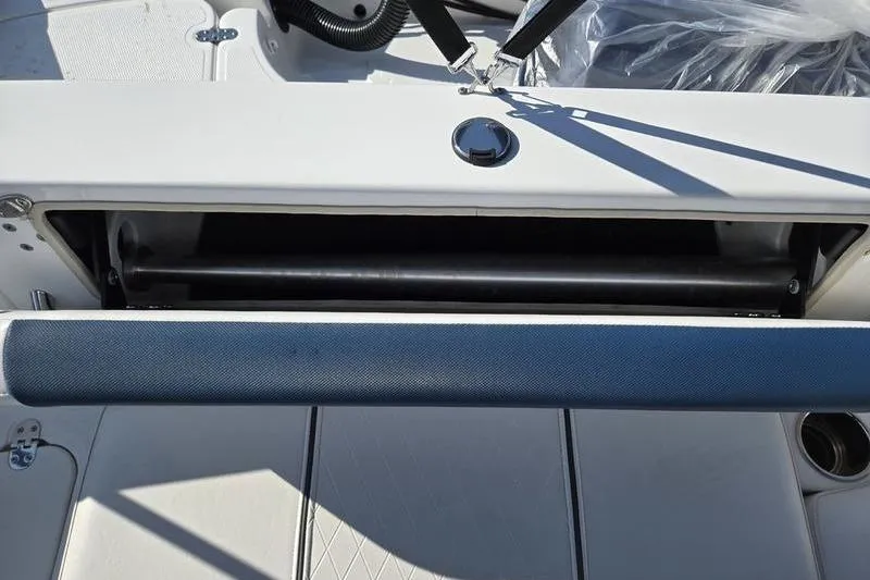 Slide: The Image of 2024 Tahoe 2150 boat interior storage compartment with cushioned seating and cup holder. - 21