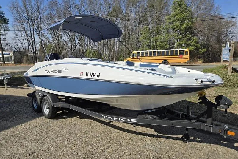 Slide: The Image of 2024 Tahoe 2150 boat on trailer with canopy, parked outdoors. - 3
