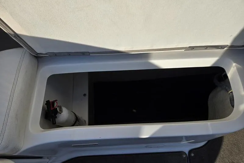Slide: The Image of Open storage compartment in a 2006 Cobalt 232 boat, featuring a fire extinguisher. - 12