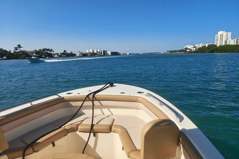 Slide: The Image of 2020 Scout 215 XSF boat cruising on a sunny day with coastal buildings in view. - 10