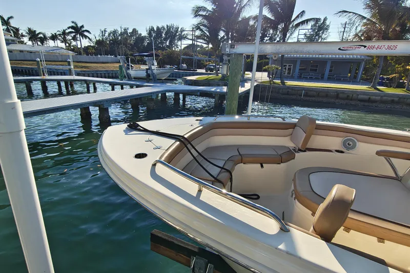 Slide: The Image of 2020 Scout 215 XSF boat docked by palm trees and clear water. - 14