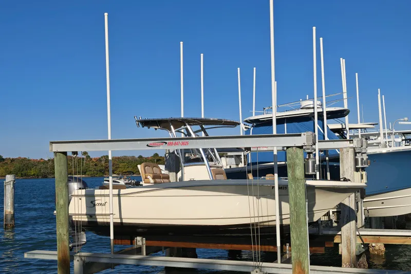 Slide: The Image of 2020 Scout 215 XSF boat docked on a lift by the water. - 19