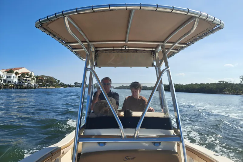 Slide: The Image of Two people on a 2020 Scout 215 XSF boat cruising on a sunny day. - 3