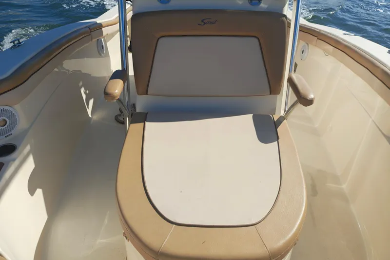 Slide: The Image of 2020 Scout 215 XSF boat interior with cushioned seating and armrests on the water. - 6