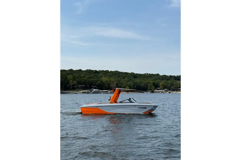 The Image of 2022 Nautique Super Air Nautique G25 boat on a lake with forested shoreline. - 1