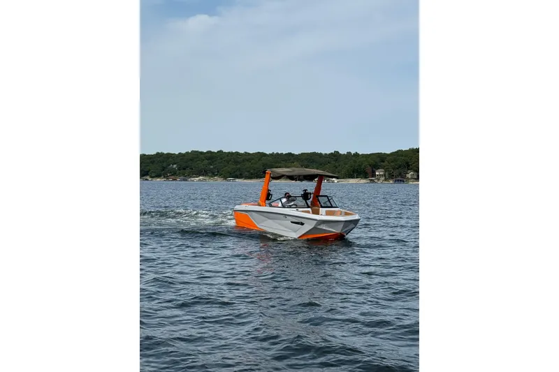 Slide: The Image of 2022 Nautique Super Air Nautique G25 boat cruising on a lake with scenic background. - 2