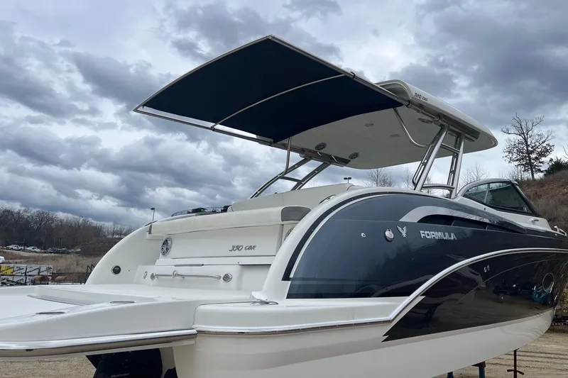 Slide: The Image of 2017 Formula 350 Crossover Bowrider boat with sleek design and canopy, under cloudy skies. - 24