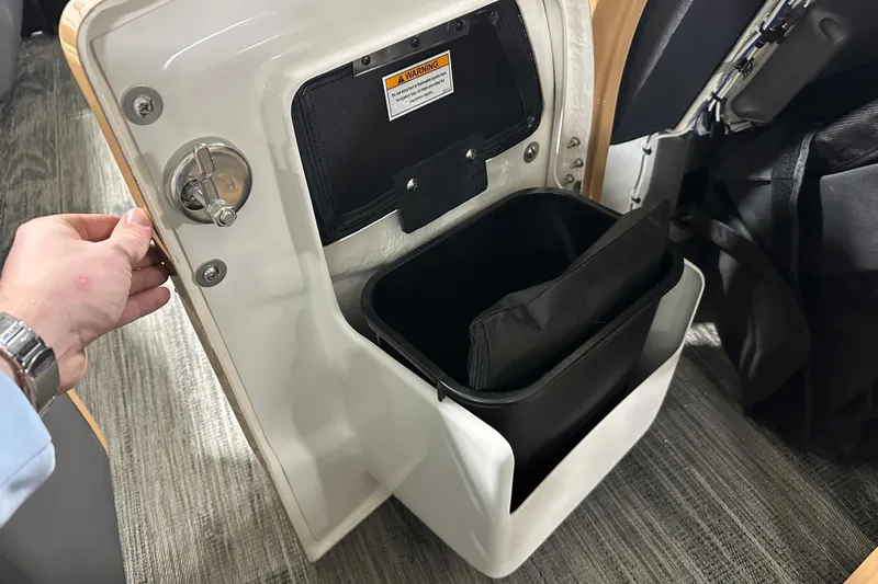 Slide: The Image of 2026 Godfrey Monaco 255 SB pontoon boat in showroom, featuring sleek black design and tan seating. - 18