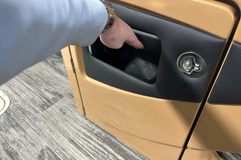 Slide: The Image of Hand accessing storage compartment in 2026 Godfrey Monaco 255 SB boat interior. - 21