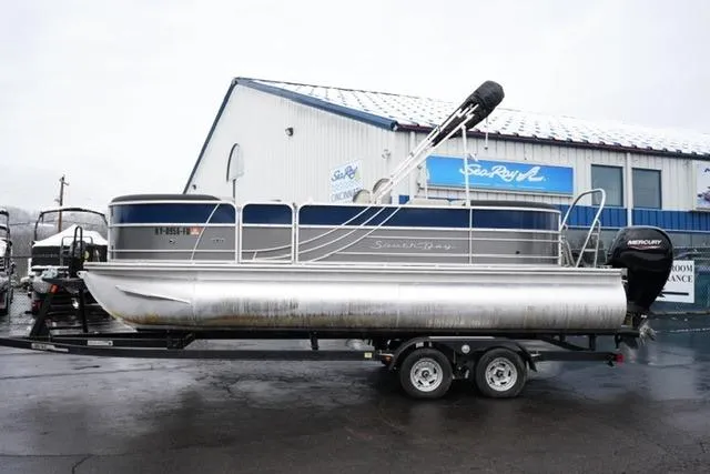 The Image of 2022 South Bay 222RS LE pontoon boat on trailer outside dealership. - 1