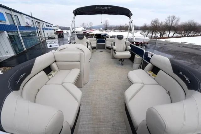 Slide: The Image of 2022 South Bay 222RS LE pontoon boat with spacious seating and canopy, docked near showroom. - 8
