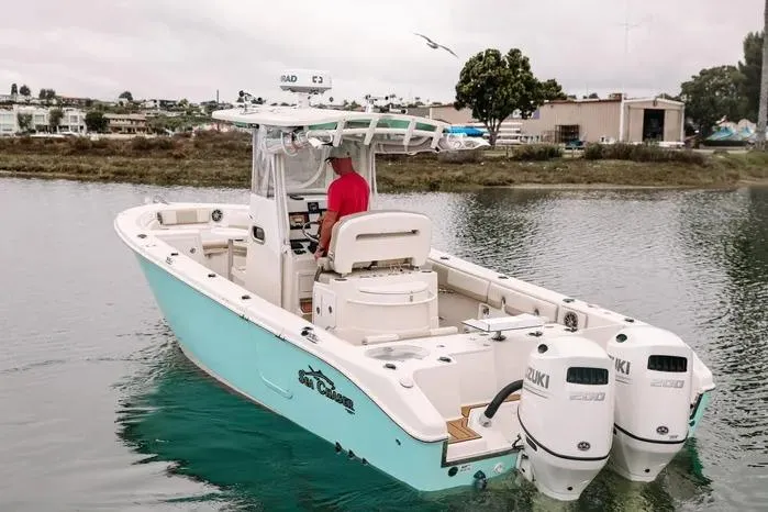 The Image of 2019 Carolina Skiff 27' Center Console boat with dual Suzuki engines on calm water. - 0