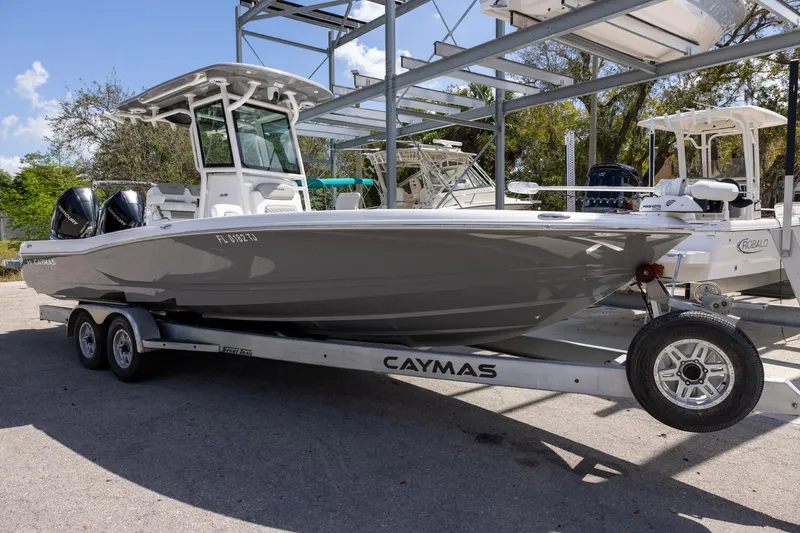 Slide: The Image of 2022 Caymas 28 HB Twin boat on trailer, parked outdoors under a clear sky. - 1