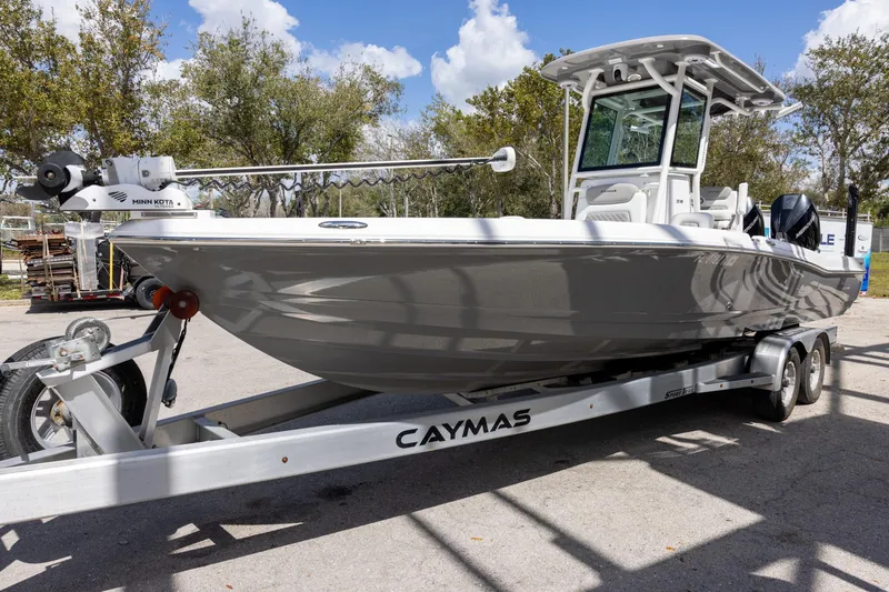 Slide: The Image of 2022 Caymas 28 HB Twin boat on trailer, parked outdoors under clear sky. - 2