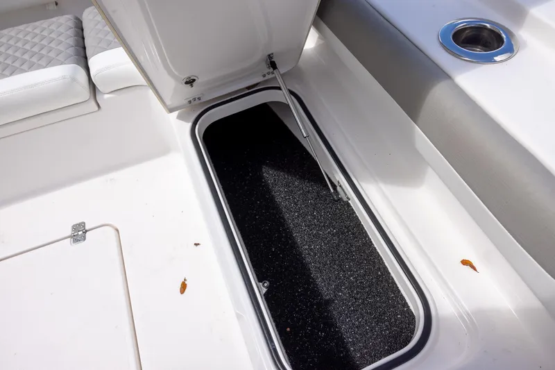 Slide: The Image of Open storage compartment on 2022 Caymas 28 HB Twin boat, featuring cushioned seating and cup holder. - 24