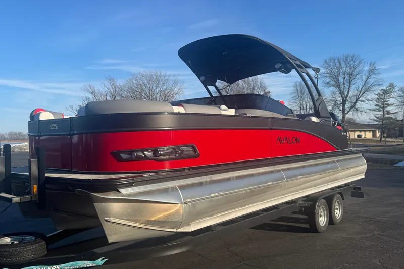 Slide: The Image of 2025 Avalon Catalina Cruise Rear Bench Windshield pontoon boat on trailer, red and black design. - 3