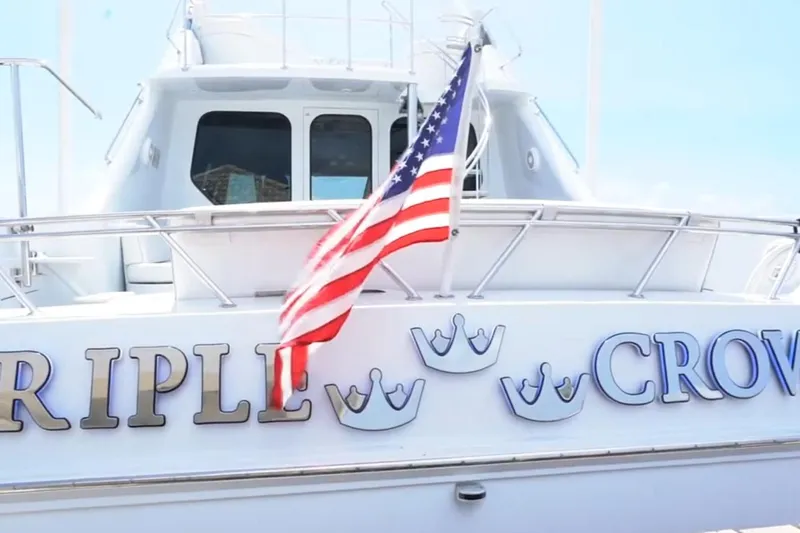 Slide: The Image of 1987 Magnum 70 Convertible yacht with American flag and "Triple Crown" text. - 32