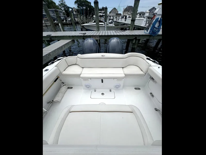 Slide: The Image of 2022 Sea Hunt Ultra 275 SE boat interior with white seating at dock. - 30