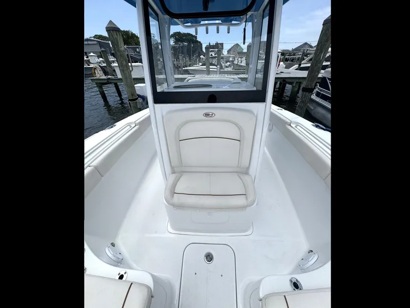 Slide: The Image of 2022 Sea Hunt Ultra 275 SE boat interior with seating and console, docked at marina. - 45