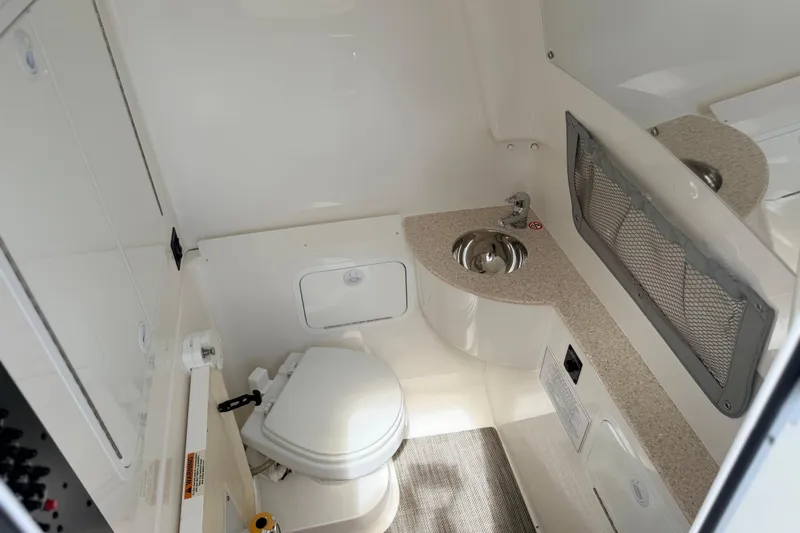 Slide: The Image of 2022 Regulator 28 boat interior with compact bathroom, featuring a toilet and sink. - 18