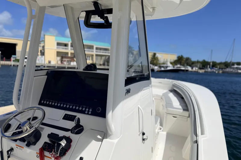 Slide: The Image of 2022 Regulator 28 boat cockpit with steering wheel and controls, docked by the marina. - 9