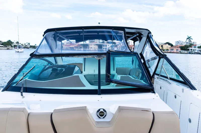 Slide: The Image of 2015 Cruisers Yachts 338 Bow Rider interior with beige seating, overlooking water. - 13