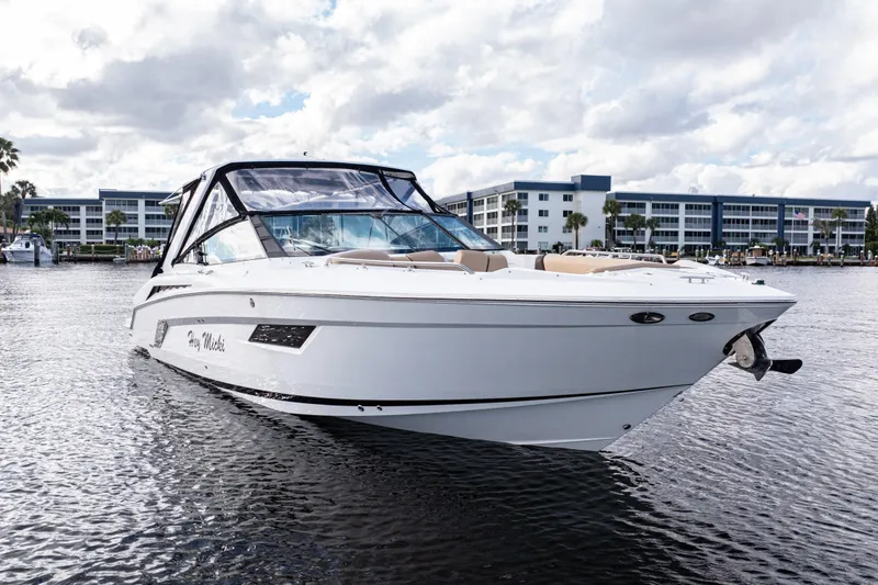 Slide: The Image of 2015 Cruisers Yachts 338 Bow Rider on water, modern design, waterfront buildings in background. - 3