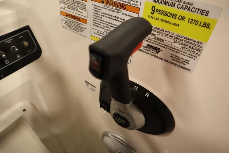 Slide: The Image of Close-up of 2024 Bayliner 2050 DX boat throttle and capacity warning labels. - 28