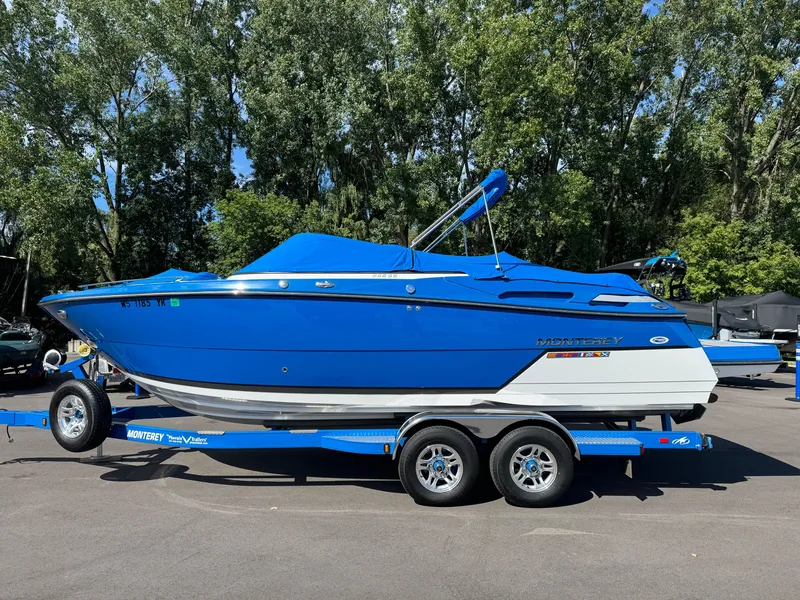 Slide: The Image of 2018 Monterey 258 Super Sport boat on trailer, vibrant blue, parked outdoors. - 3