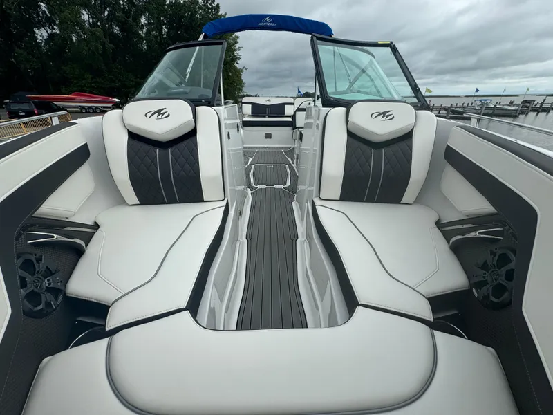 Slide: The Image of 2018 Monterey 258 Super Sport boat interior with white and black seating, docked by trees. - 33