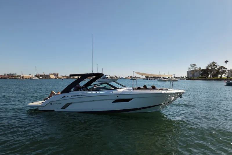 Slide: The Image of 2019 Cruisers Yachts 338 Bow Rider on calm water, sunny day, coastal backdrop. - 70