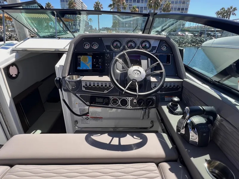 Slide: The Image of 2019 Cruisers Yachts 338 IO helm with modern controls and navigation, docked near palm trees. - 10