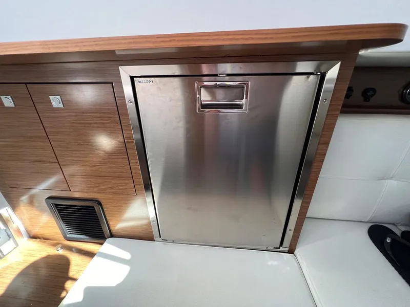 Slide: The Image of 2019 Cruisers Yachts 338 IO interior with stainless steel fridge and wooden cabinetry. - 30