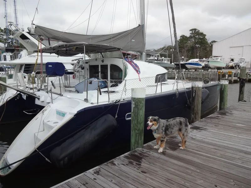 Slide: The Image of 2003 Lagoon 410 catamaran docked with a dog on the pier. - 2