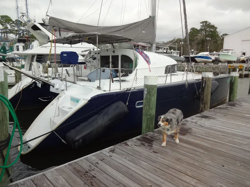 Slide: The Image of 2003 Lagoon 410 catamaran docked with a dog nearby. - 3