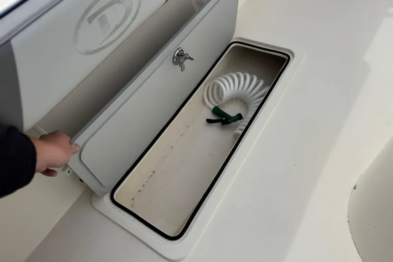 Slide: The Image of Storage compartment on 2023 Defiance 220 Admiral EX boat with coiled hose inside. - 12