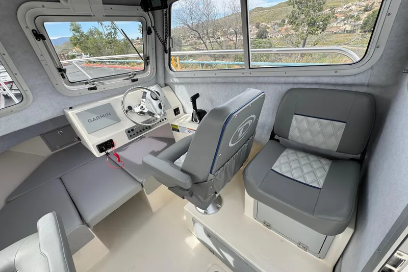 Slide: The Image of Interior of 2023 Defiance 220 Admiral EX boat with steering wheel and seating. - 23